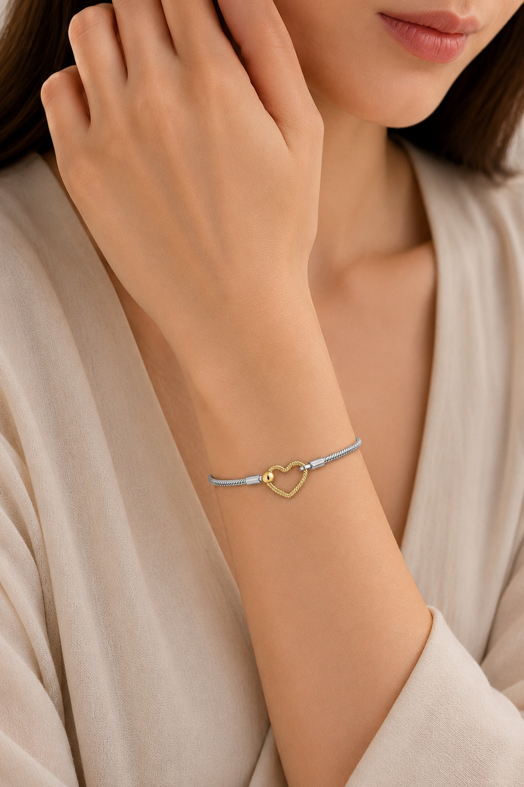 Two-tone bracelet with a golden heart closure on a wrist