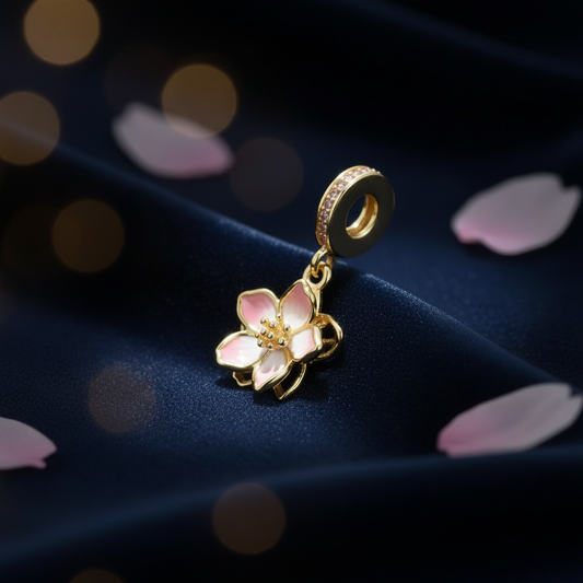 Gold cherry blossom dangle charm with pink enamel petals on dark velvet background